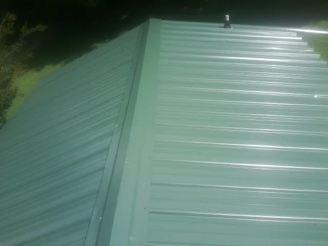 New green metal panels meeting at the ridge of a roof — Flat Roof Repair work by our crew in Pinetown