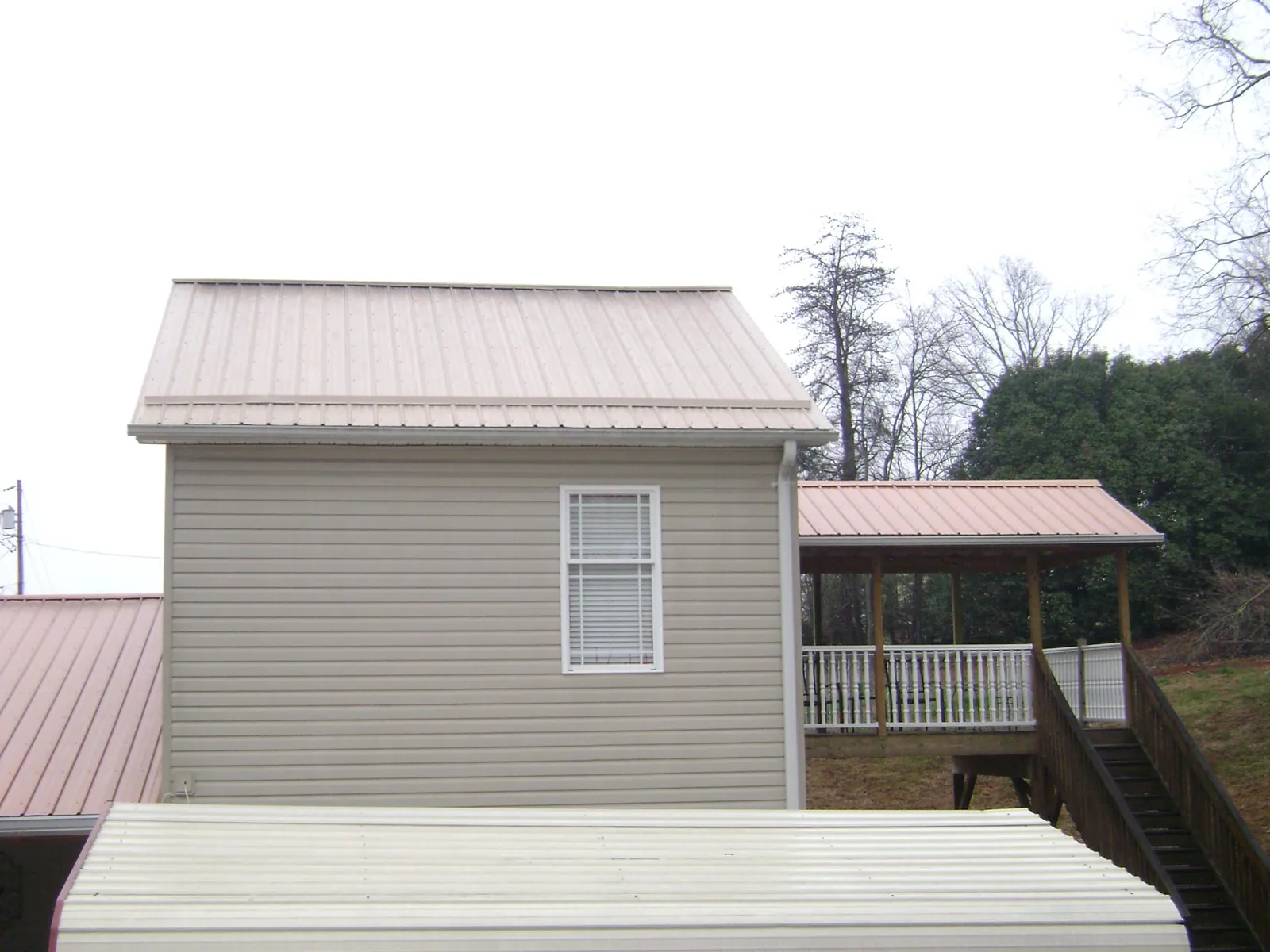 Tan metal roofs on a two story addition and attached porch, from a Roof Replacement job in Pinetown