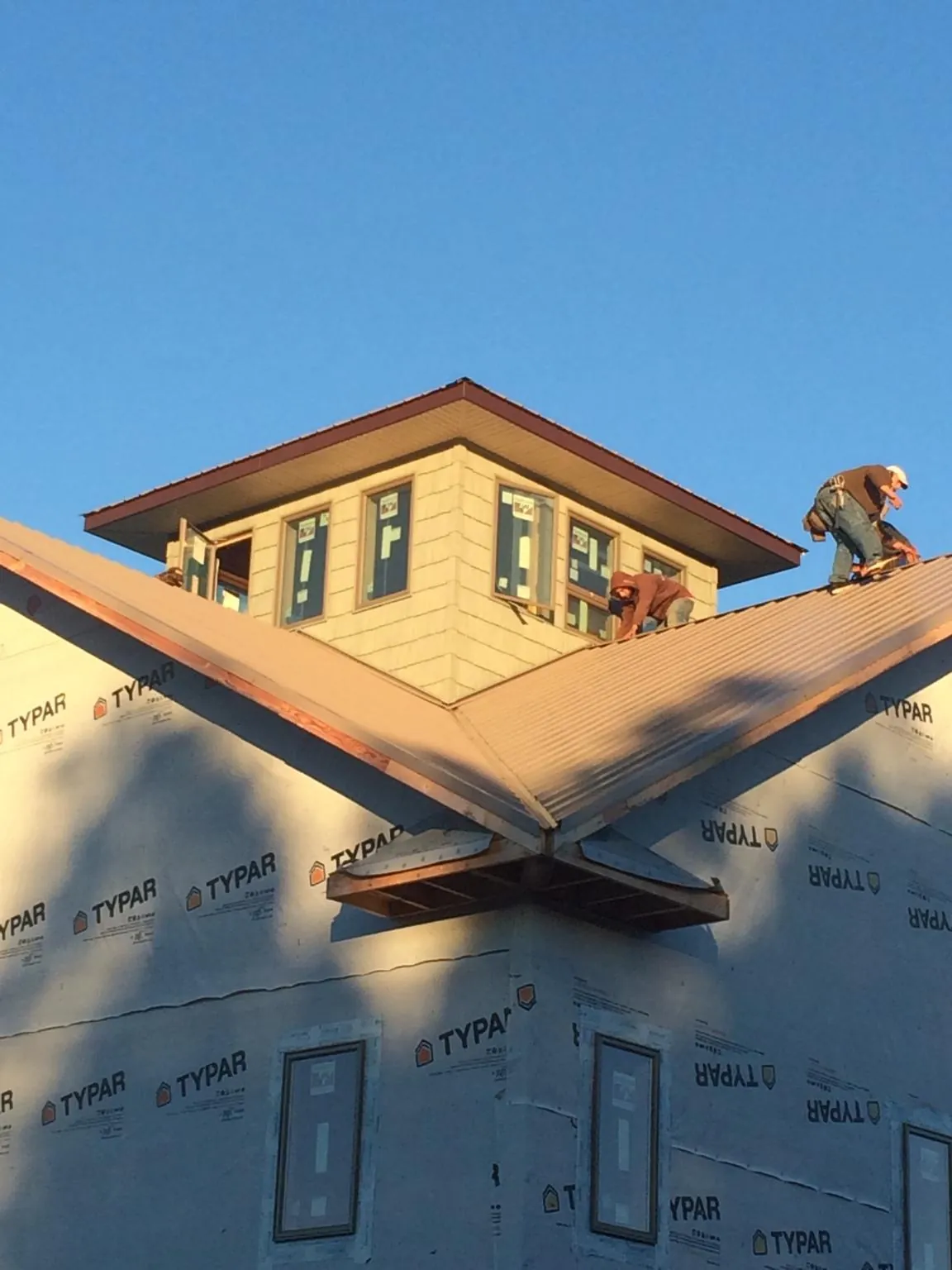 Roofers working around a rooftop cupola on a new metal roof at sunset — Roof Waterproofing in Pinetown by Roofing Brothers